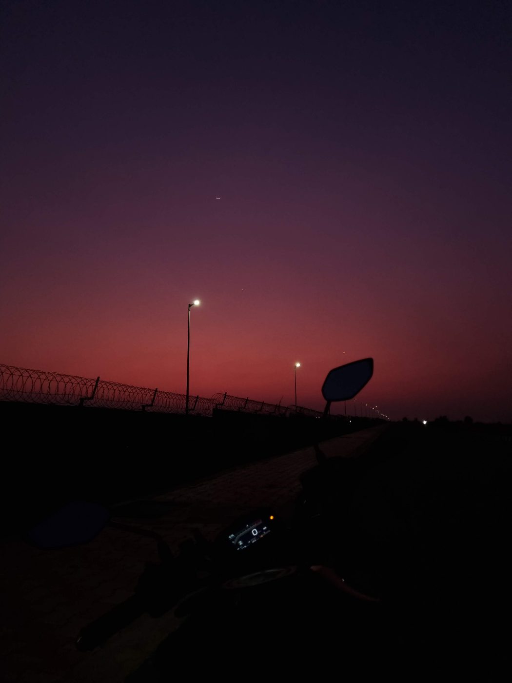A pink dusk sky over the highway, from the bike