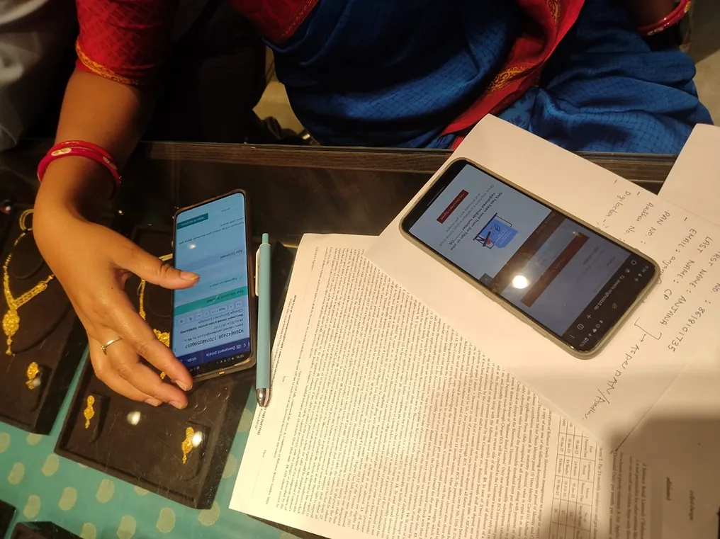 A customer using the scheme on a phone next to the printed scheme paperwork.